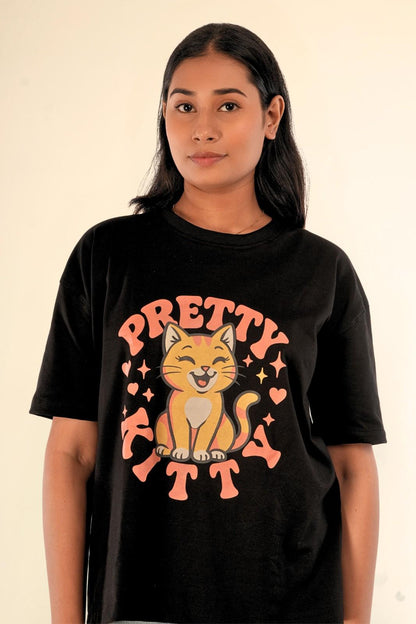 Front detail of black oversized women's t-shirt with Pretty Kitty cat graphic. Premium screen-printed design featuring adorable cat illustration with peach hearts and stars. High-resolution view of Berrys & Cigaredes graphic print quality.