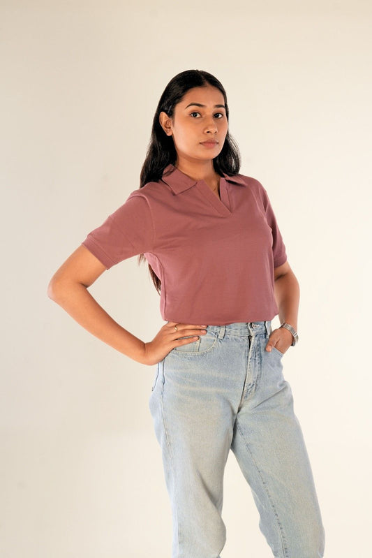 Woman in dusty rose polo shirt front view, styled with light blue jeans, confident pose