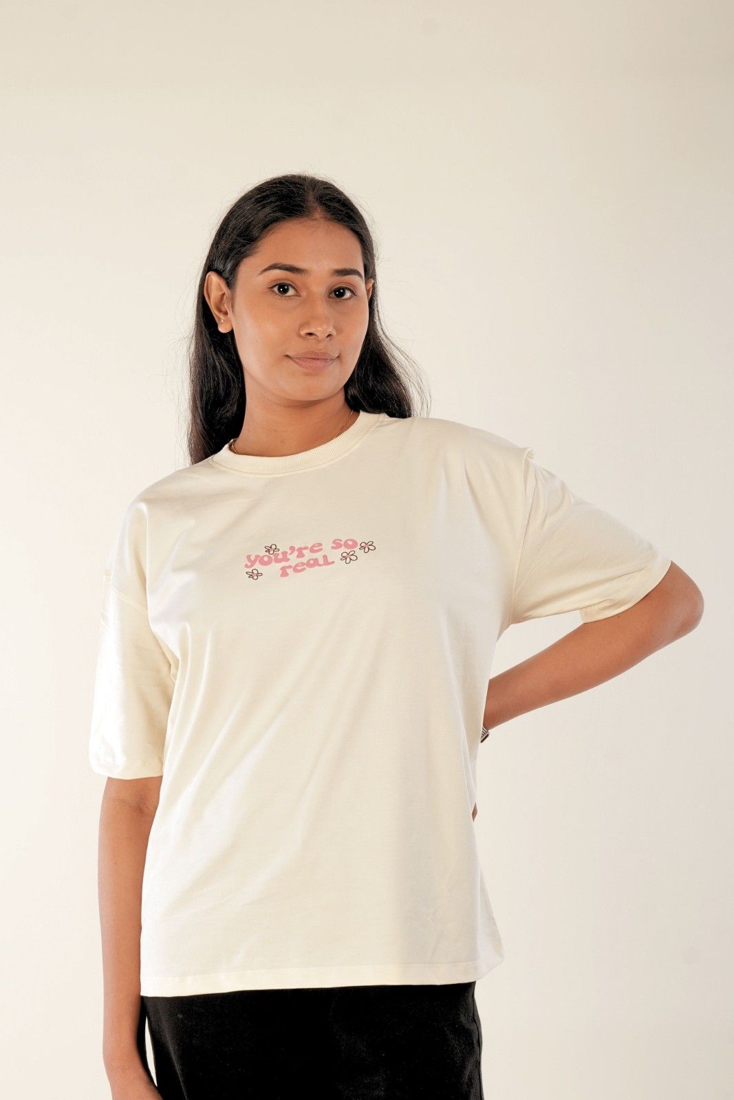Women's oversized graphic t-shirt in cream with pink 'You're So Real' text and flowers, casual minimalist design